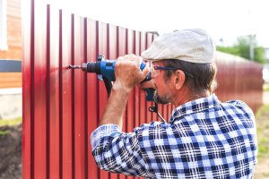 Man installing red privacy fence in Palm Beach