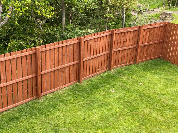 Stained wooden fence along a green lawn in Palm Beach County, FL