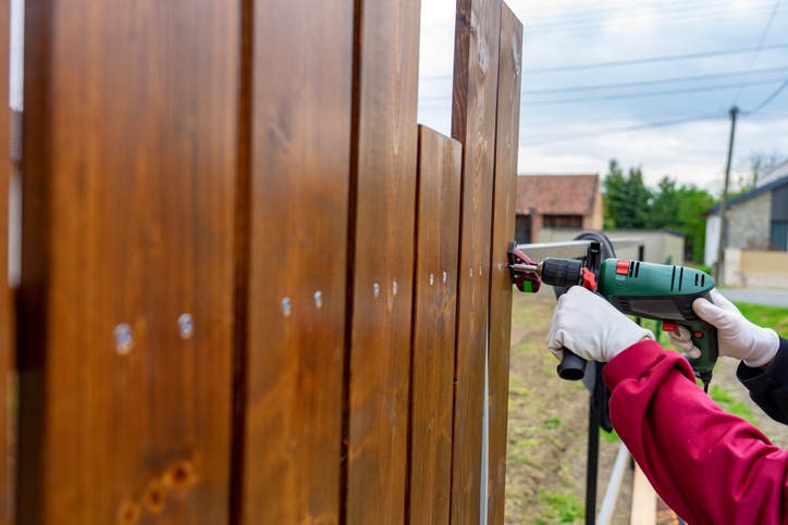 Person using a drill machine on a wooden fence in Palm Beach County, FL